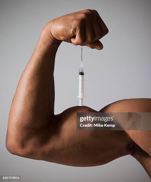 syringe perched on a flexed muscular arm - steroids stock pictures, royalty-free photos & images