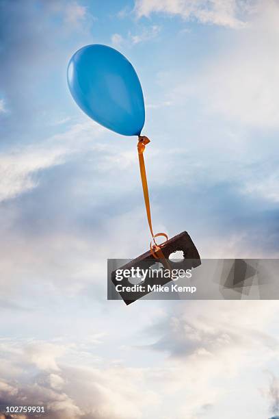 balloon tied to a brick - leicht stock-fotos und bilder