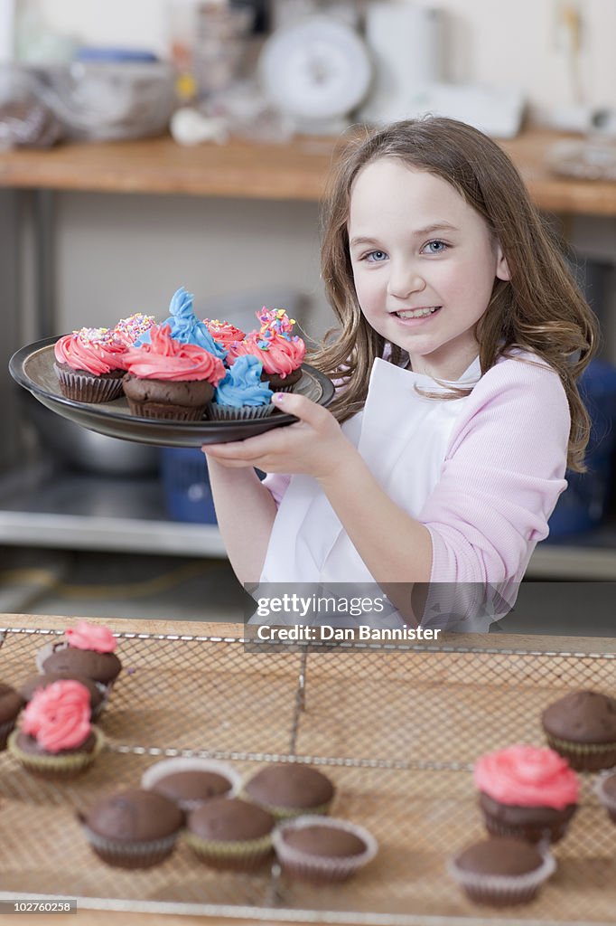 Young girl holding a plate of cupcakes