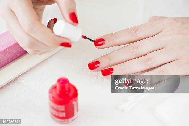 woman painting her nails with red nail polish - vernis à ongles photos et images de collection