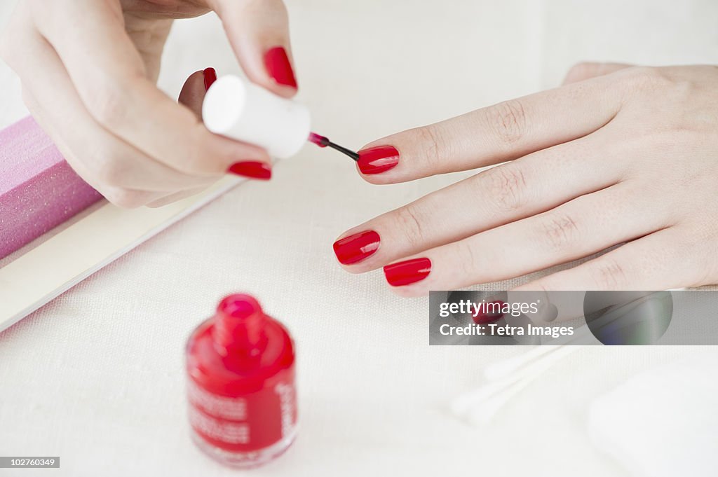 Woman painting her nails with red nail polish