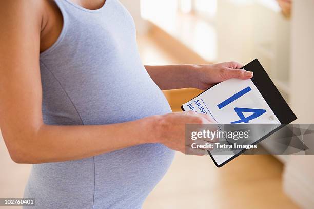 pregnant woman looking a calendar - tummy time stock pictures, royalty-free photos & images