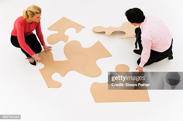 business people work at finishing puzzle - big puzzle photos et images de collection