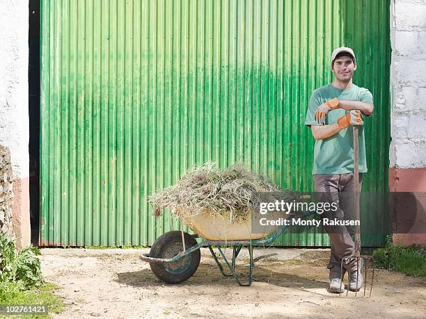 man with wheelbarrow full of hay - full frontal stock-fotos und bilder