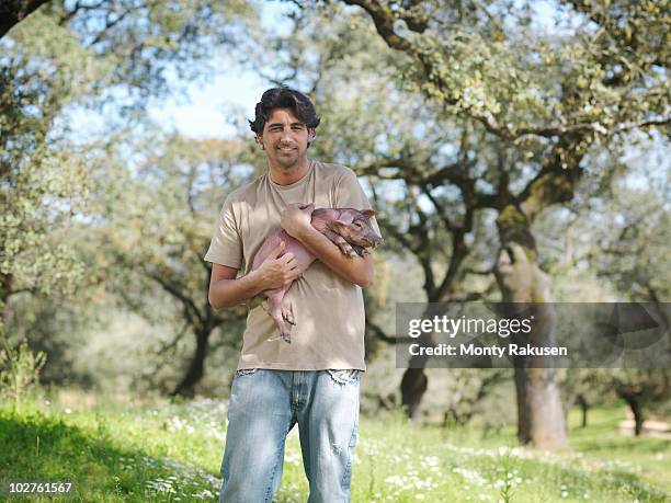 man holding a piglet in field on farm - man holding pig stock pictures, royalty-free photos & images