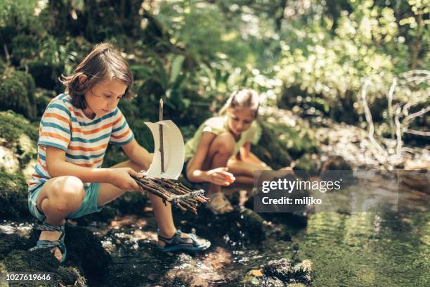 kinder spielen mit boot am fluss - kids at river stock-fotos und bilder