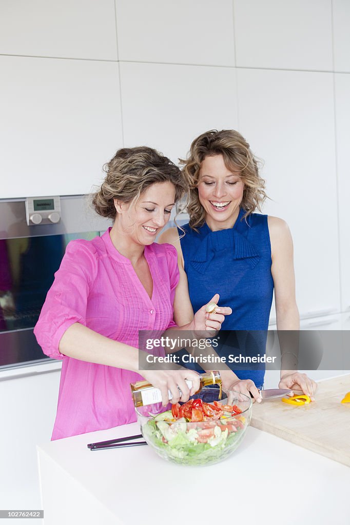 Two woman preparing salad with vinegar