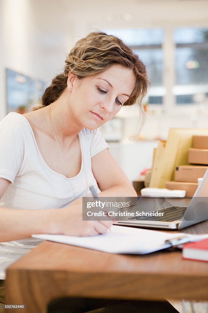 Woman writing on a paper at office