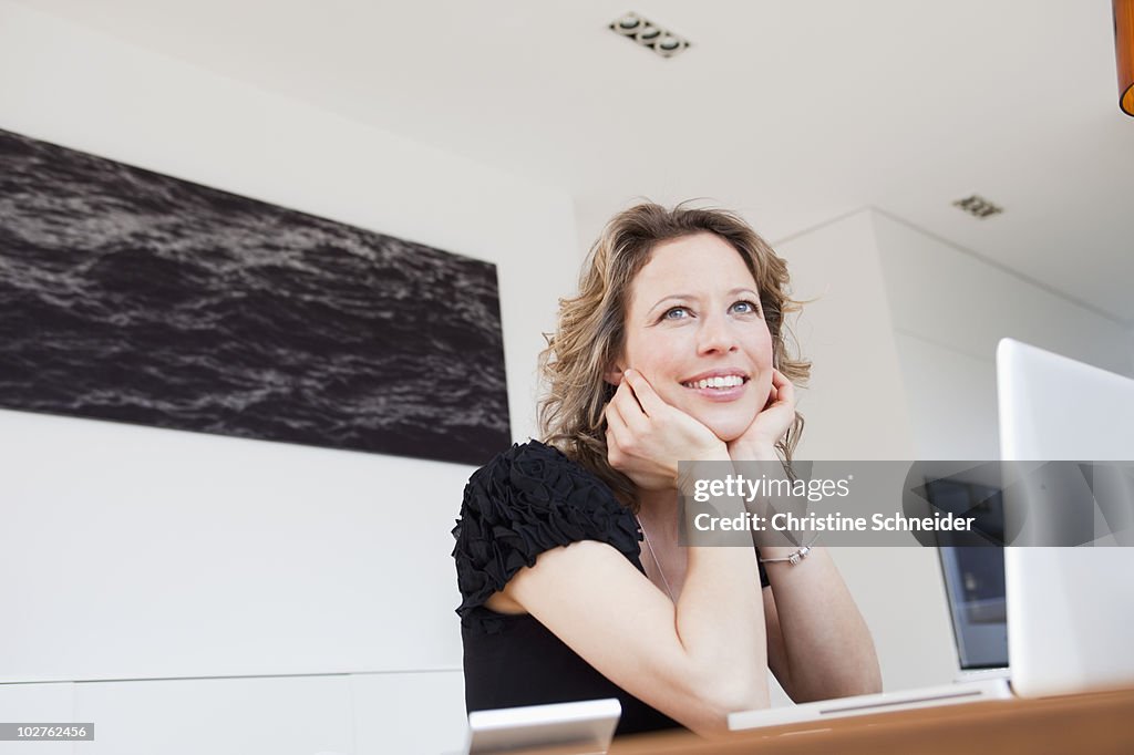 Woman with laptop thinking