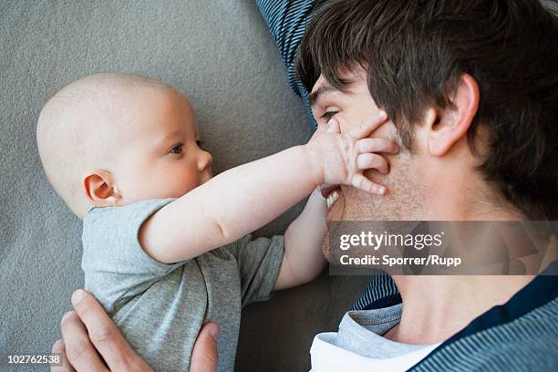 baby touching fathers face - gripping stock pictures, royalty-free photos & images