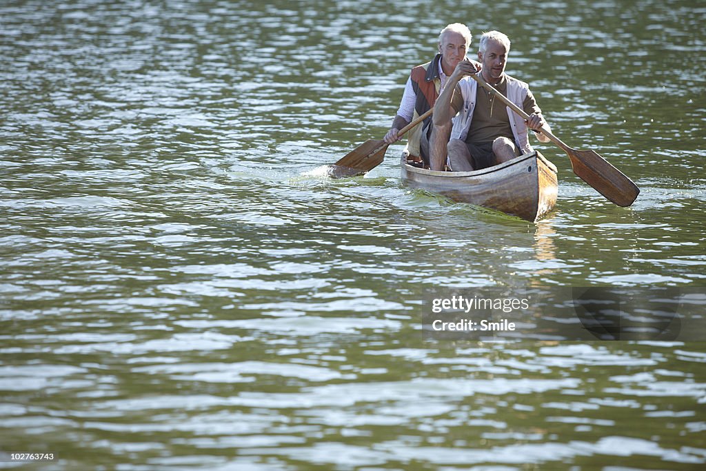 Two senior men paddling canoe on lake