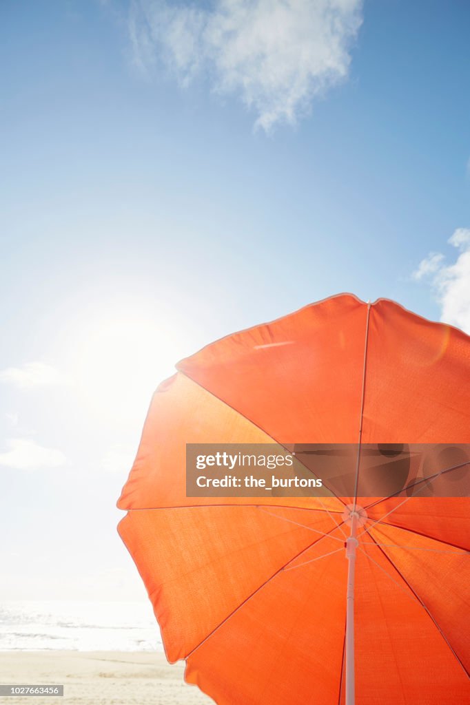 Orange parasol on the beach against sky