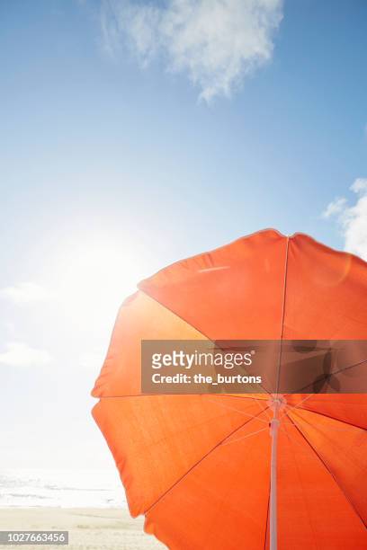 orange parasol on the beach against sky - parasol stockfoto's en -beelden