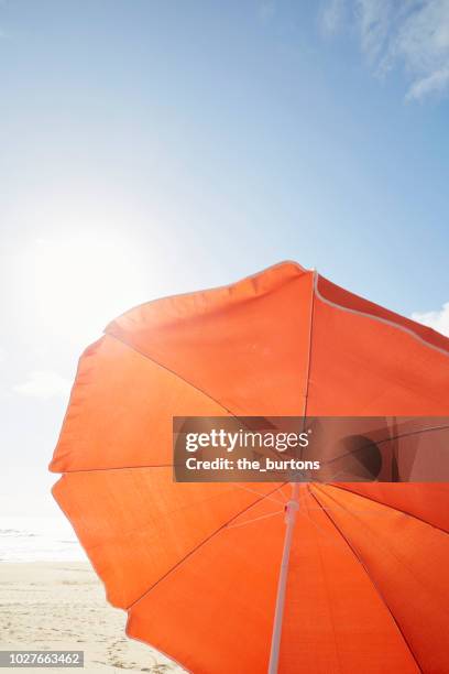 orange parasol on the beach against sky - red parasol stock pictures, royalty-free photos & images