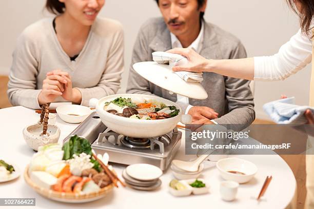 family being served dinner at table - hot pots stockfoto's en -beelden