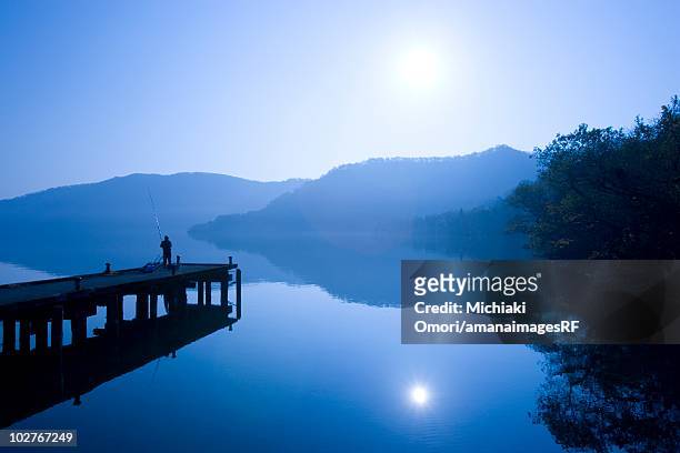 person fishing off a pier, kazuno, akita prefecture, japan - akita prefecture stock pictures, royalty-free photos & images
