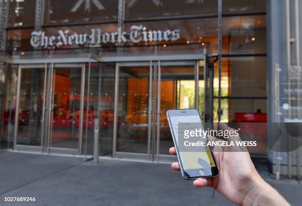 Smartphone displaying a New York Times opinion piece titled "I Am Part of the Resistance Inside the Trump Administration" is held up in this...