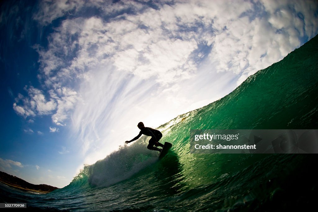 Ocean and cloudy sky with silhouette of surfer