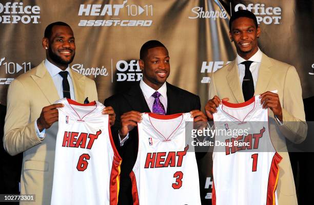 LeBron James, Dwyane Wade and Chris Bosh of the Miami Heat show off their new game jerseys before a press conference after a welcome party at...