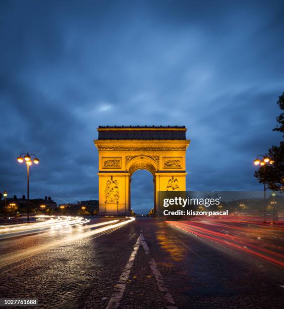 arc de triomphe monument with light trail of cars in paris during night , france - arc de triomphe stock-fotos und bilder