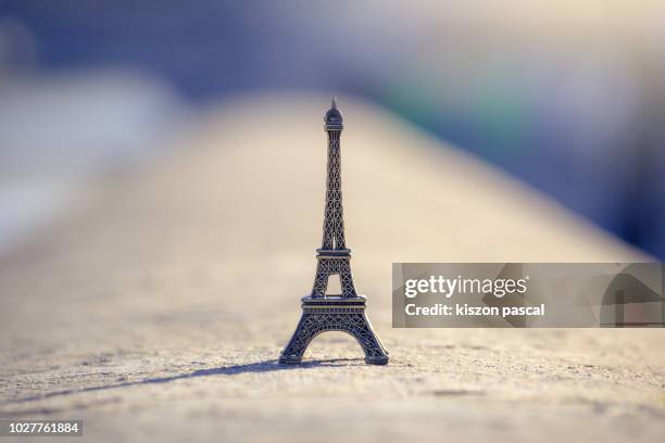 defocused miniature eiffel tower on a stone with sunlight  , paris , france - eiffel tower paris stock-fotos und bilder