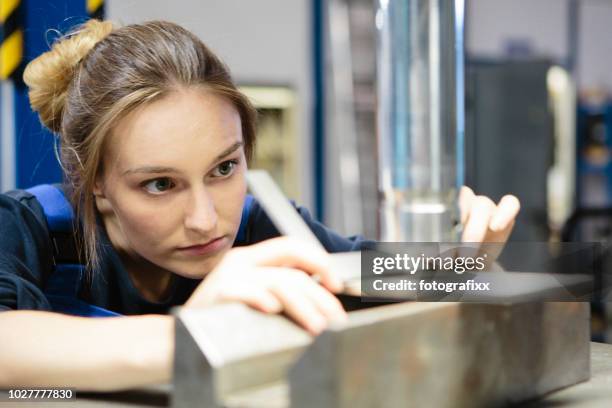young female trainee controls the flatness of a sheet metal steel at a hydraulic press - sheet metal stock pictures, royalty-free photos & images