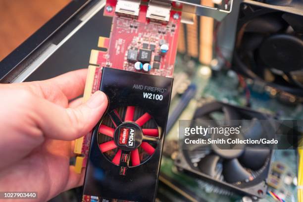 Hand of a man installing an AMD Firepro Graphical Processing Unit , aka graphics card, in a cryptocurrency mining computer for mining the Bitcoin...