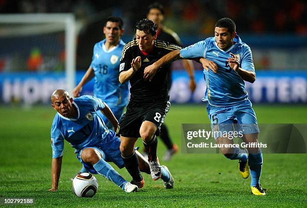 Mesut Oezil of Germany is challenged by Walter Gargano of Uruguay during the 2010 FIFA World Cup South Africa Third Place Play-off match between...