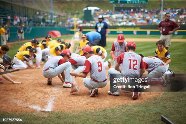 Little League World Series Championship: Team Japan and team Southeast Region collecting dirt from field as souvenirs after Championship game at...
