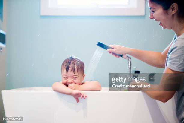 down's syndrome sweet boy in the bath while mom is washing him. - taking a bath stock pictures, royalty-free photos & images