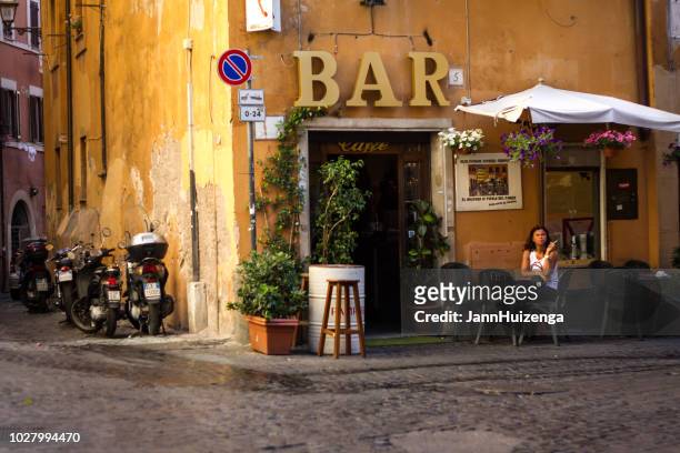rome, italië: vrouw zit buiten koffiebar roken - italianen stockfoto's en -beelden