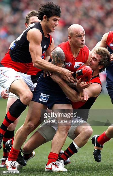 Andrew Welsh and Patrick Ryder of the Bombers tackle Nathan Jones of the Demons during the round 15 AFL match between the Melbourne Demons and the...