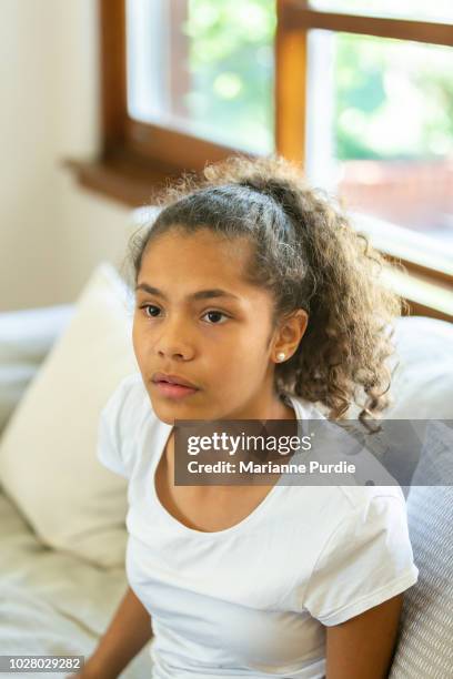 a young girl sitting on a lounge looking upwards - aboriginal girl stock pictures, royalty-free photos & images