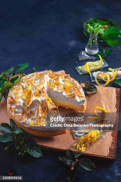 lemon tart with meringue, leaves, lemon zest, spatula and whisk on a dark background. a missing piece of the pie. home cooked desserts concept - curd cheese stock pictures, royalty-free photos & images