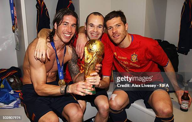 Andres Iniesta , Sergio Ramos and Xabi Alonso of Spain pose with the trophy in the Spanish dressing room after they won the 2010 FIFA World Cup at...