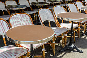Typical tables and rattan chairs outside of a sidewalk cafe in Paris, France.