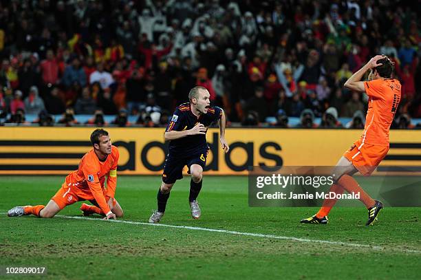 Andres Iniesta of Spain celebrates scoring the winning goal as Joris Mathijsen and Rafael Van der Vaart of the Netherlands look on dejected during...