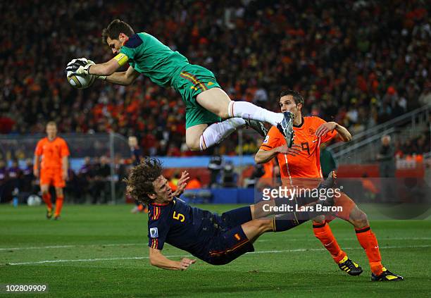 Iker Casillas of Spain catches the ball ahead of Robin Van Persie of the Netherlands as Carles Puyol of Spain falls to the ground during the 2010...