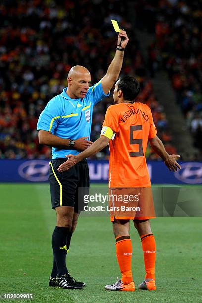 Referee Howard Webb issues Giovanni Van Bronckhorst of the Netherlands a yellow card during the 2010 FIFA World Cup South Africa Final match between...