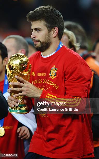 Gerard Pique of Spain lifts the World Cup trophy as the Spain team celebrate victory following the 2010 FIFA World Cup South Africa Final match...