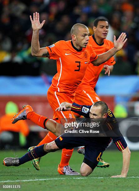 Andres Iniesta of Spain falls under the challenge of John Heitinga of the Netherlands, which results in Heitinga being shown a second yellow card and...