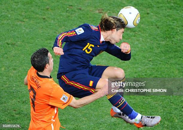 Spain's defender Sergio Ramos heads the ball as Netherlands' striker Robin van Persie looks on during the 2010 FIFA football World Cup final between...