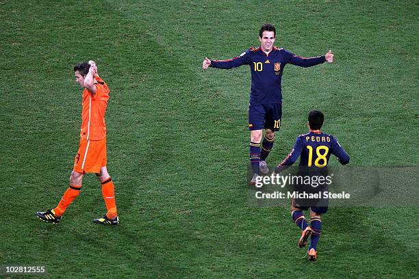 Francesc Fabregas and Pedro Rodriguez of Spain celebrate winning the World Cup as a dejected Robin van Persie of the Netherlands walks past during...