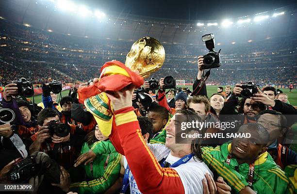 Spain's defender Sergio Ramos raises the trophy in front of photographers as he celebrates winning the 2010 World Cup football final Netherlands vs....