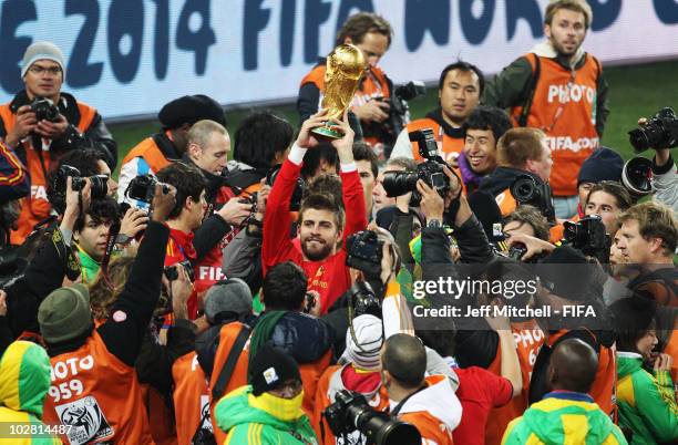 Gerard Pique of Spain holds the World Cup aloft after the 2010 FIFA World Cup South Africa Final match between Netherlands and Spain at Soccer City...