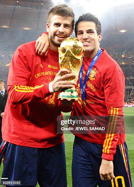 Spain's defender Gerard Pique and Spain's midfielder Cesc Fabregas pose with the trophy as they celebrate winning the 2010 World Cup football final...
