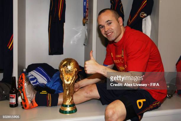 Andres Iniesta of Spain poses with the trophy in the Spanish dressing room after they won the 2010 FIFA World Cup at Soccer City Stadium on July 11,...
