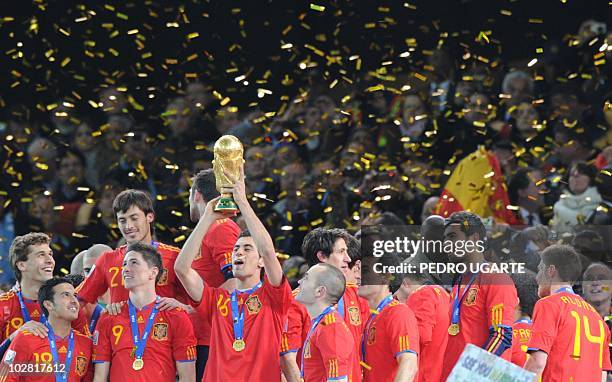 Spain's midfielder Sergio Busquets raises the trophy after the award ceremony following the 2010 FIFA football World Cup between the Netherlands and...