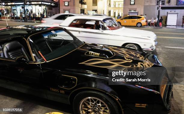 Man in a classic car slows to take a picture of the Pontiac Firebird Trans Am from Burt Reynold's film "Smokey and the Bandit" is seen in front of...