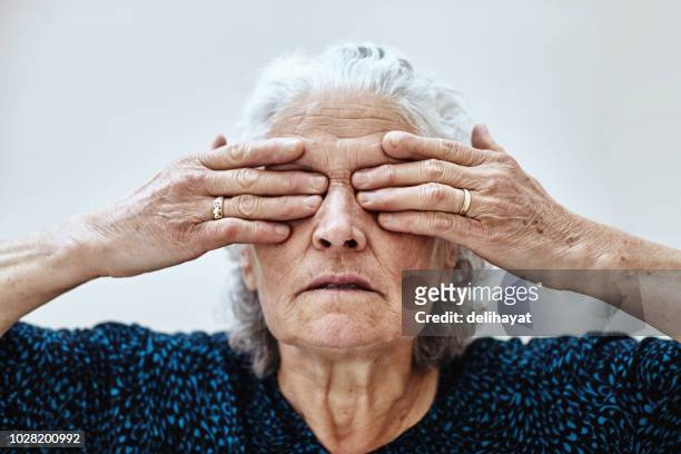 senior vrouw die betrekking hebben op ogen met handen - self closing stockfoto's en -beelden